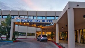 The Pacific Bay Hotel entrance with a covered driveway and a car parked in front. - Pacific Bay Hotel (Tamuning)