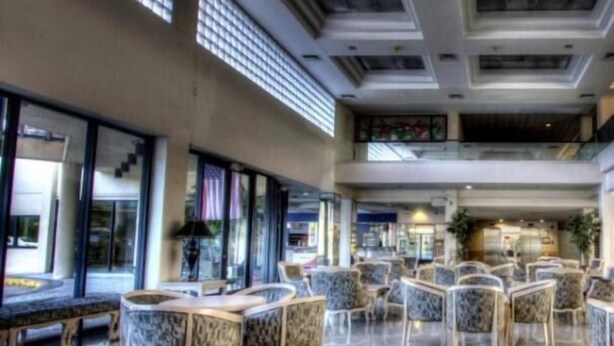A spacious lobby with high ceilings, large windows, and a variety of seating arrangements including sofas and chairs. - Pacific Bay Hotel (Tamuning)