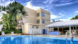 A swimming pool with a building in the background. - Pacific Bay Hotel (Tamuning)