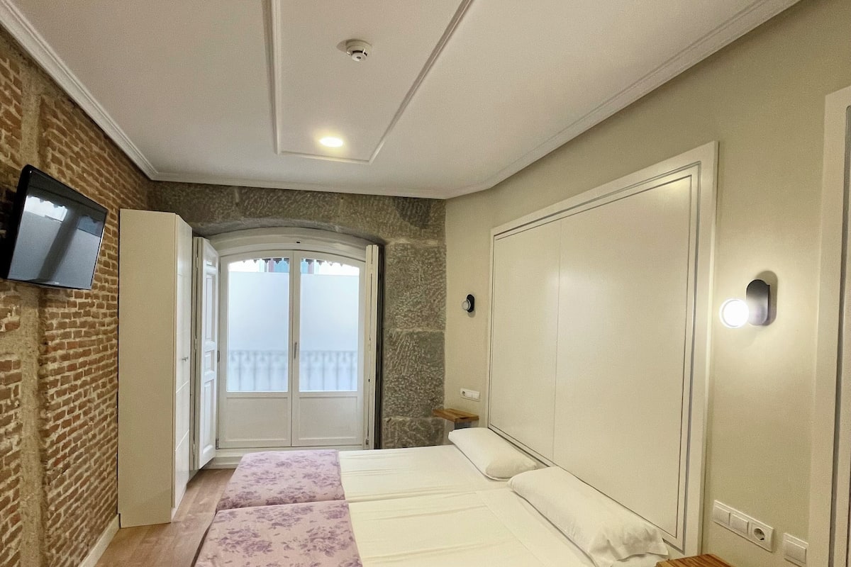 A bedroom with a bed, a wardrobe, a television, and a balcony door.