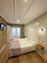 Ein Schlafzimmer mit Bett, Kleiderschrank, Fernseher und Balkontür.
