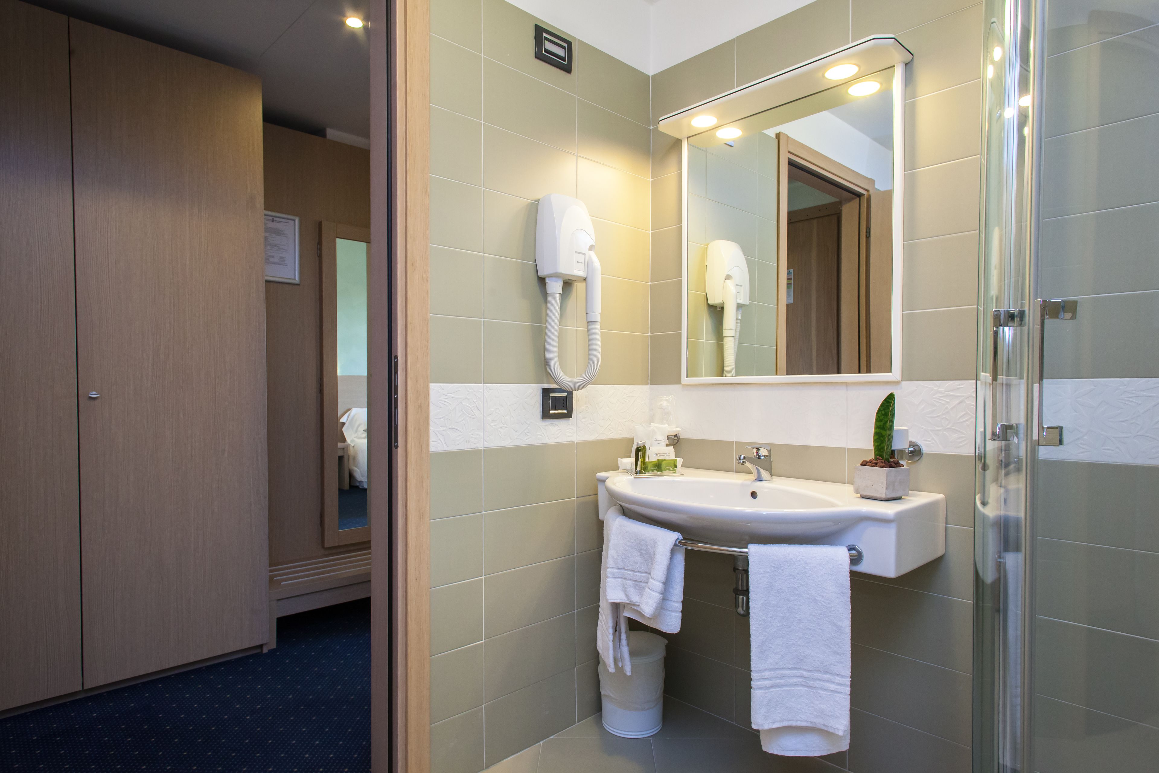 Un baño de hotel con lavabo, espejo y secador de pelo.