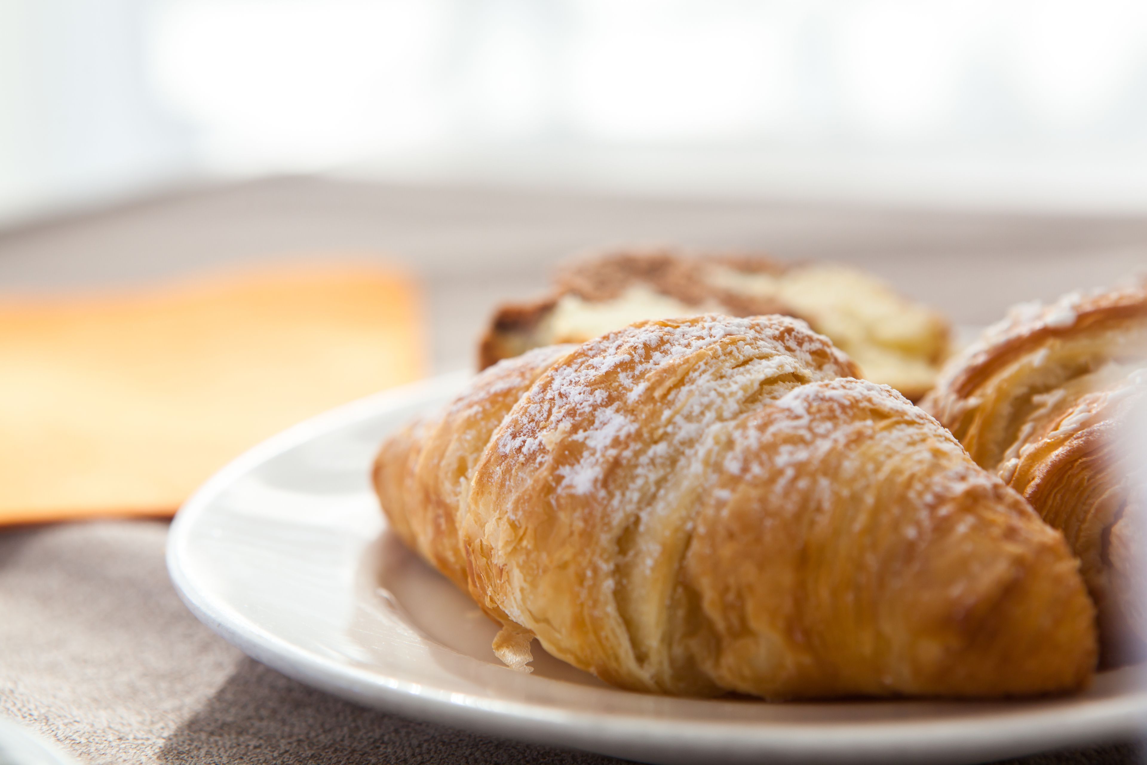 A plate with croissants and a pastry on a table.
