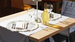 Une table dressée avec une nappe blanche, des couverts en argent et une bouteille de vin blanc.