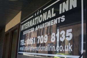 A sign for International Inn, listing contact information and services.
