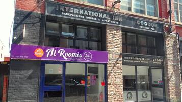 Un edificio con varios establecimientos, incluyendo un hostal internacional, un alojamiento tipo cápsula y el restaurante indio Al Roomis.