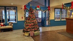 Ein weihnachtlich geschmücktes Foyer mit einem großen Weihnachtsbaum, Geschenken und festlichen Girlanden.