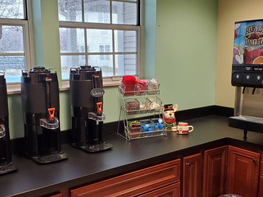 A kitchen area with coffee makers, a water dispenser, and a juice machine.