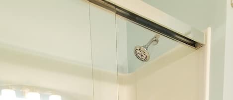 A glass-enclosed shower with a white towel hanging on the door handle.