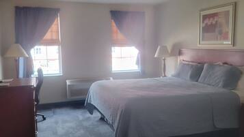 A hotel room with a bed, two bedside tables, a desk, and a chair.