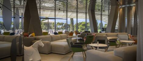 A modern interior with a large sectional sofa, colorful chairs, and a unique ceiling design.