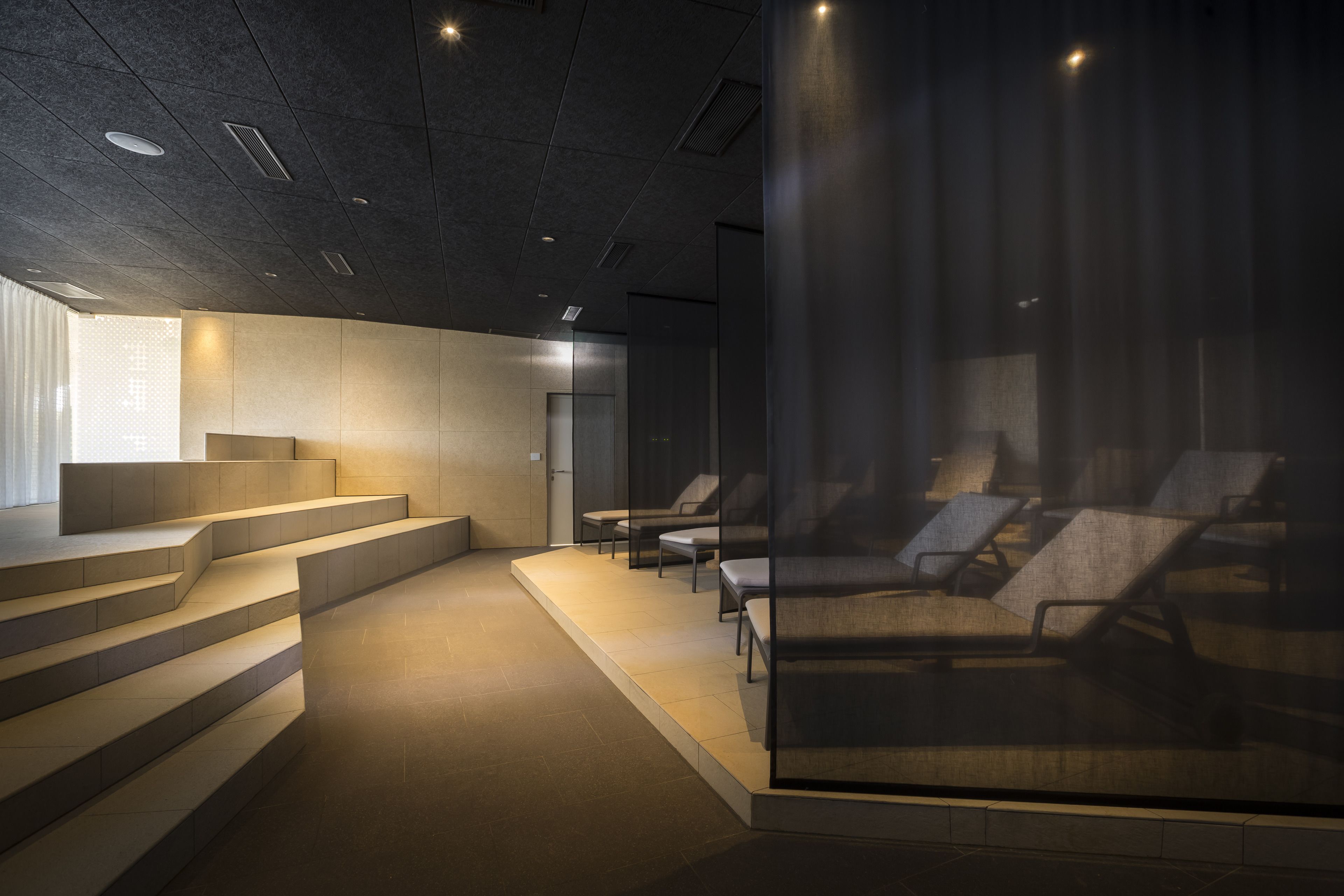 A modern interior with a staircase leading to a seating area with lounge chairs.