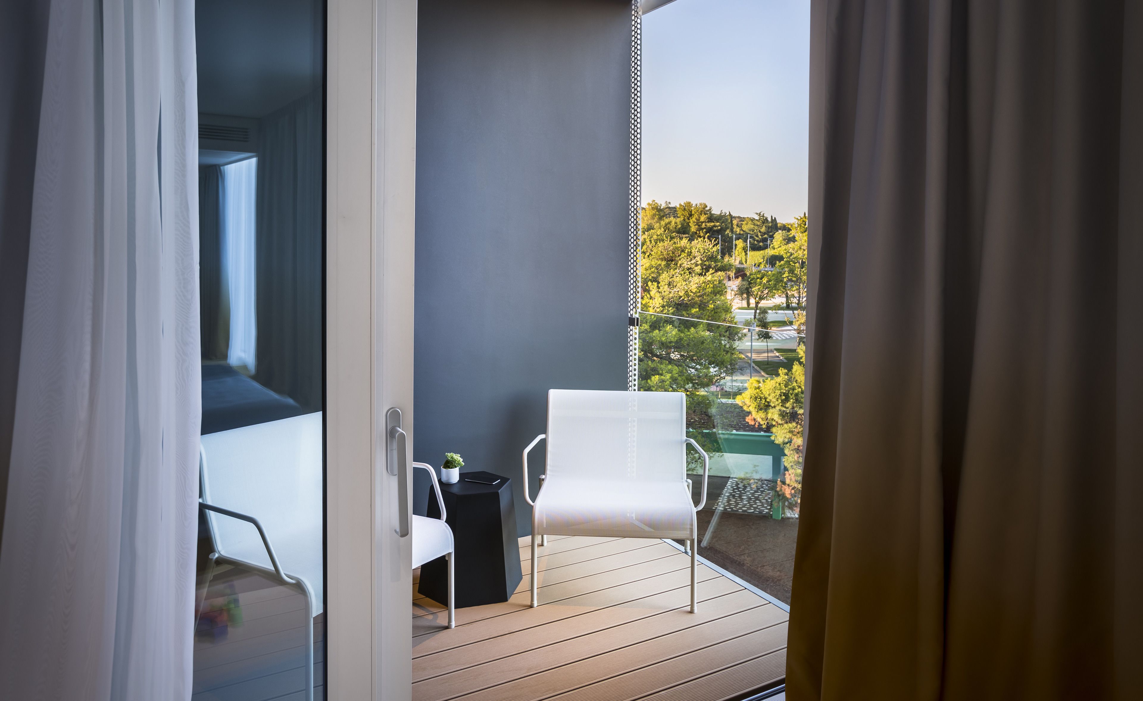 En balkon med en hvid stol, et lille bord og en potteplante.