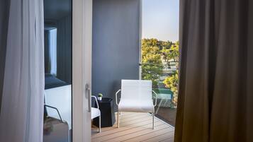 En balkon med en hvid stol, et lille bord og en potteplante.