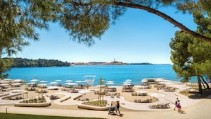 Un complexe hôtelier situé en bord de mer, doté de chaises longues, de parasols et offrant une vue sur l’océan.