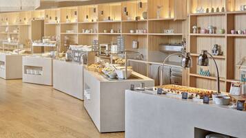Un café moderno con varios mostradores de atención, estantes de madera con objetos decorativos y una distribución limpia y organizada.
