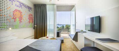Habitación de hotel moderna con una cama grande, un escritorio, un televisor de pantalla plana y un balcón con vistas a la ciudad.