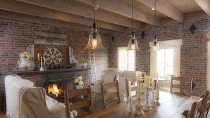 Une salle à manger rustique avec une cheminée en briques, une table à manger en bois et des chaises.