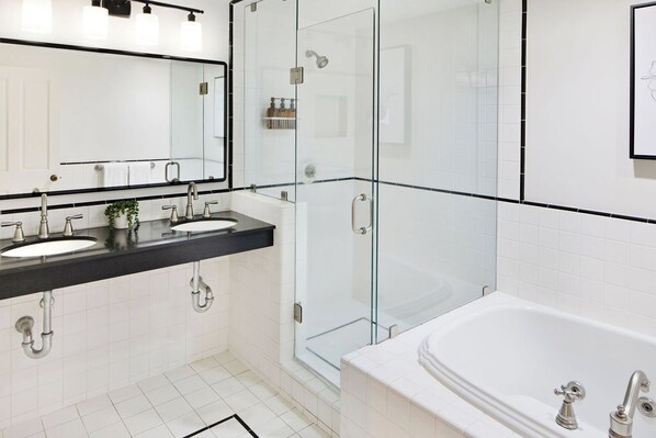 A modern bathroom with a double sink, a glass-enclosed shower, and a standalone bathtub.