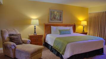 A hotel room with a bed, a chair, a nightstand, and a lamp.