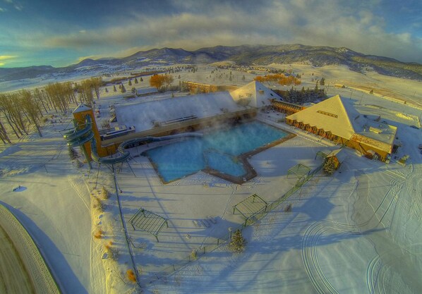 A snow-covered resort with a swimming pool, a hot tub, and a ski lift.