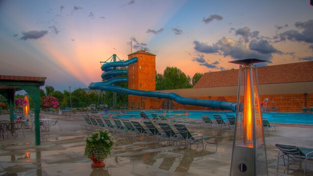 A pool area with lounge chairs, a water slide, and a tall tower. - Fairmont Hot Springs Resort (Anaconda)