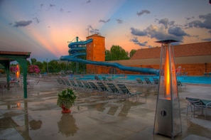 Un espace piscine avec des chaises longues, un toboggan et une haute tour.