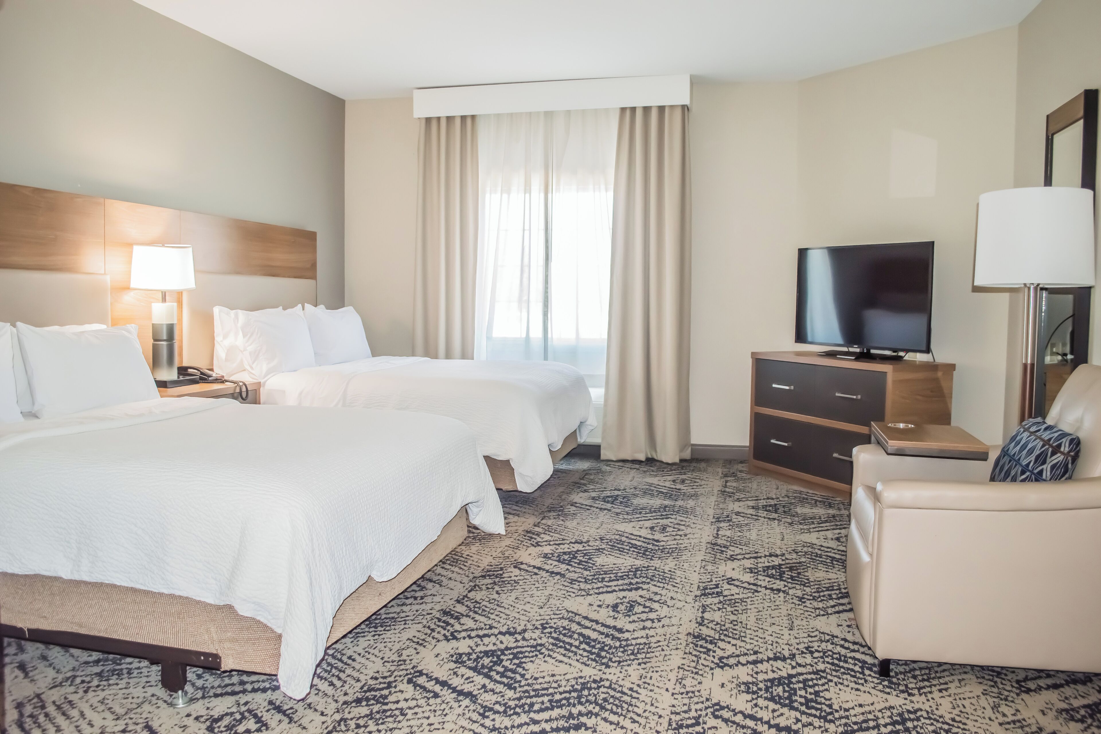 Una habitación de hotel con dos camas, televisión, escritorio y silla.