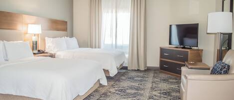 Una habitación de hotel con dos camas, televisión, escritorio y silla.