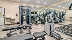Ein modernes Fitnessstudio mit verschiedenen Trainingsgeräten, darunter Laufbänder und Kraftgeräte, sowie einer großen Spiegelwand.