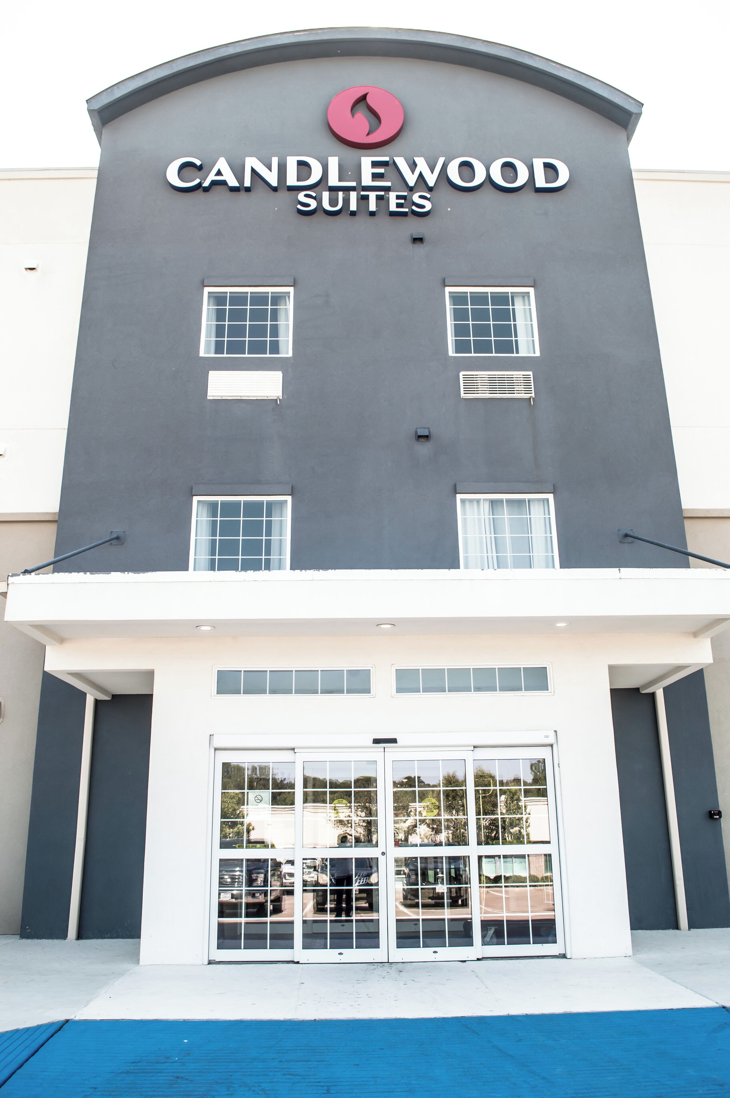 Un bâtiment sur lequel on peut lire l’inscription « CANDLEWOOD SUITES » et qui est doté d’un ensemble de portes doubles.