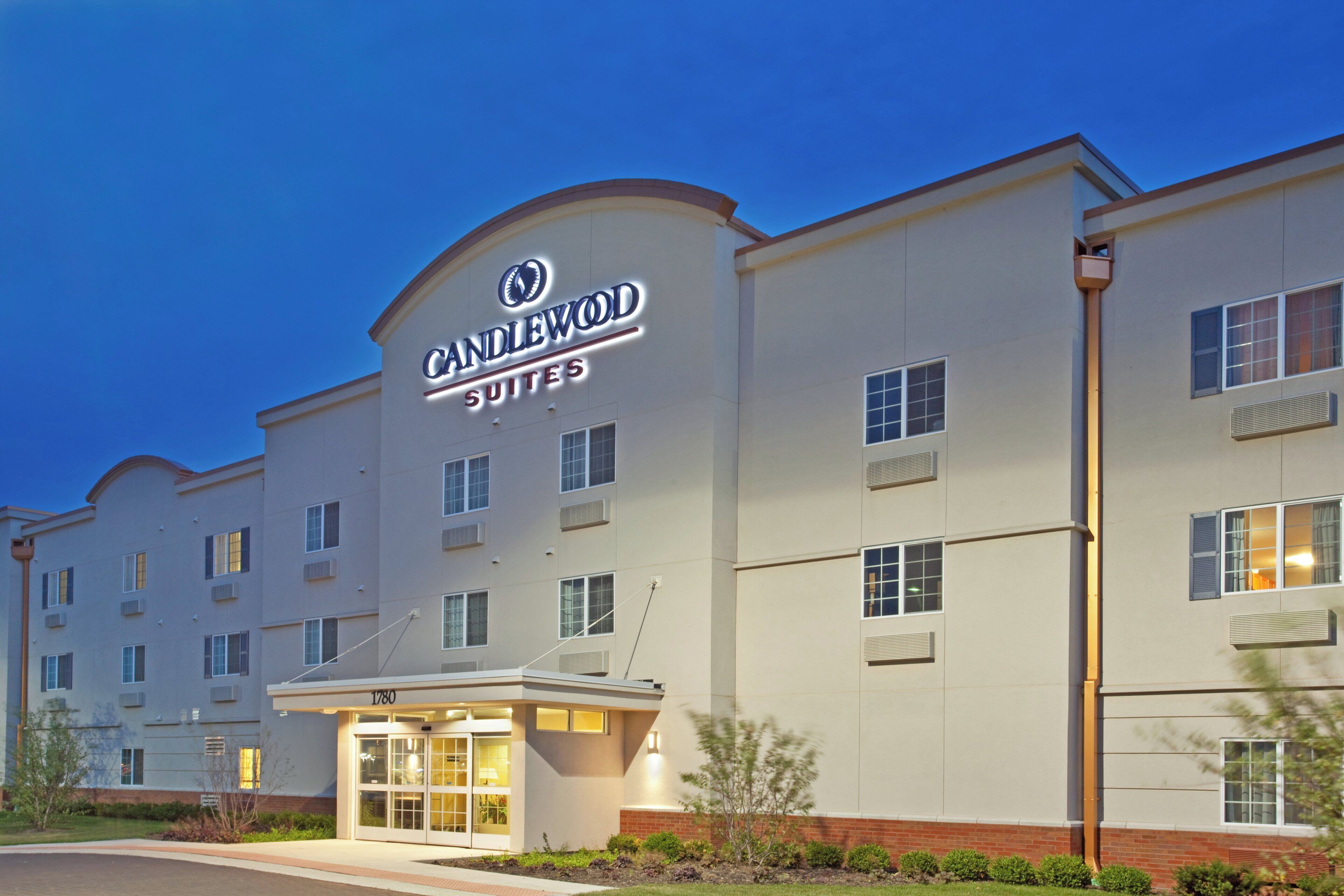 A hotel with a prominent 'Candlewood Suites' sign, a brick entrance, and multiple windows.