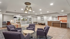 A spacious lobby with a reception desk, seating area with chairs and a round table, and a large window with a view of the outdoors. - Candlewood Suites Elgin by IHG (Elgin)
