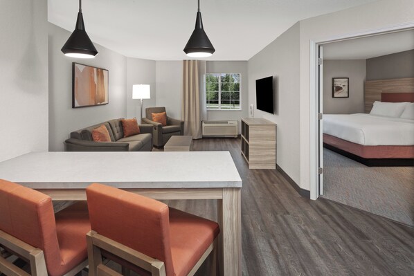 A hotel room with a dining area, a sofa, a TV, and a bed. - Candlewood Suites Elgin by IHG (Elgin)