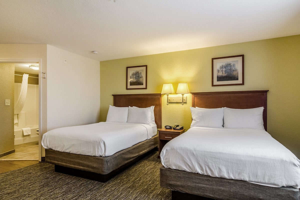 Ein Hotelzimmer mit zwei Betten, einem Badezimmer und einem Flur.