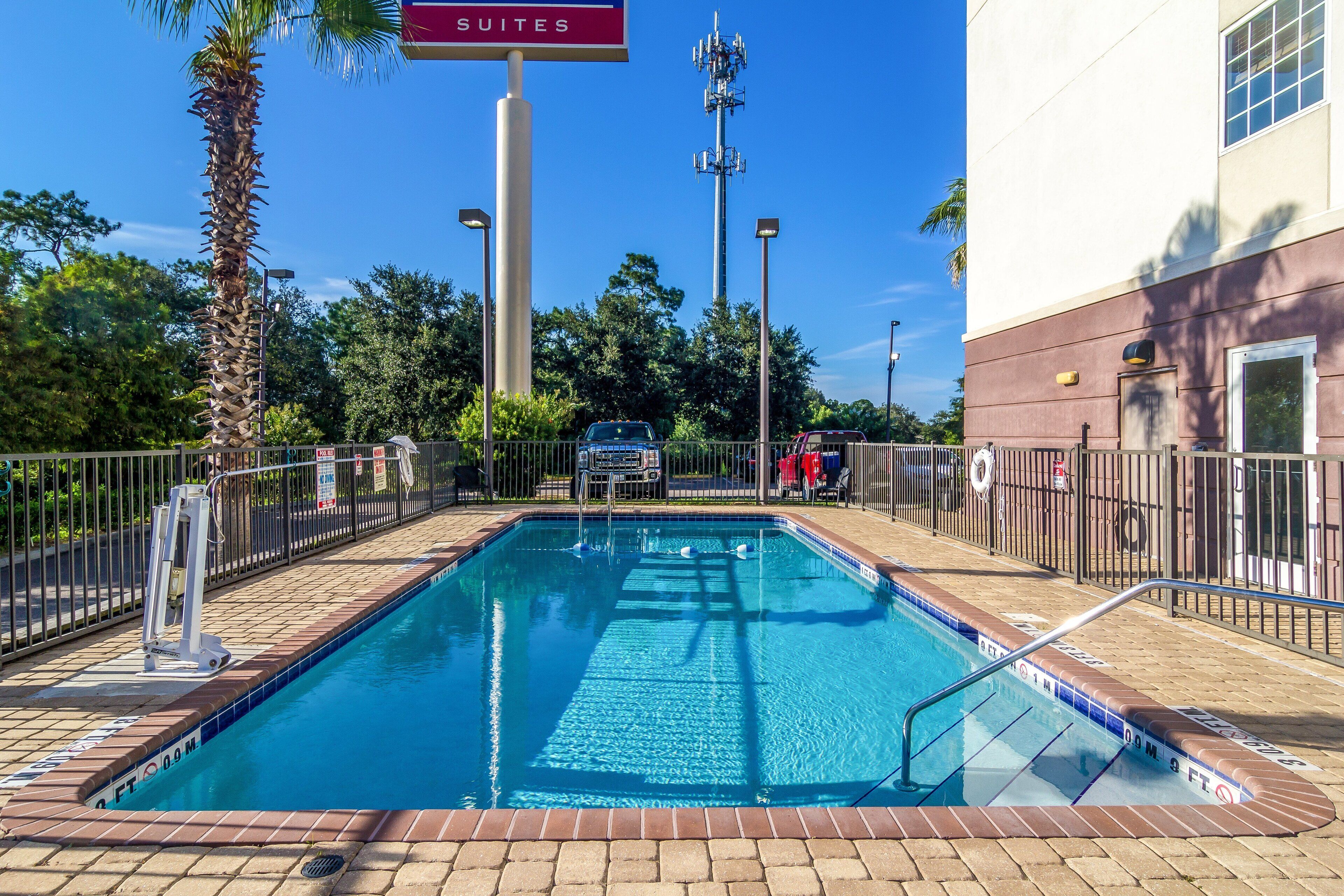 A rectangular pool with a tiled edge, surrounded by a metal fence, and a sign indicating 'SUITES' above.