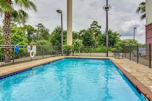 Relax by the pool surrounded by lush greenery and palm trees.