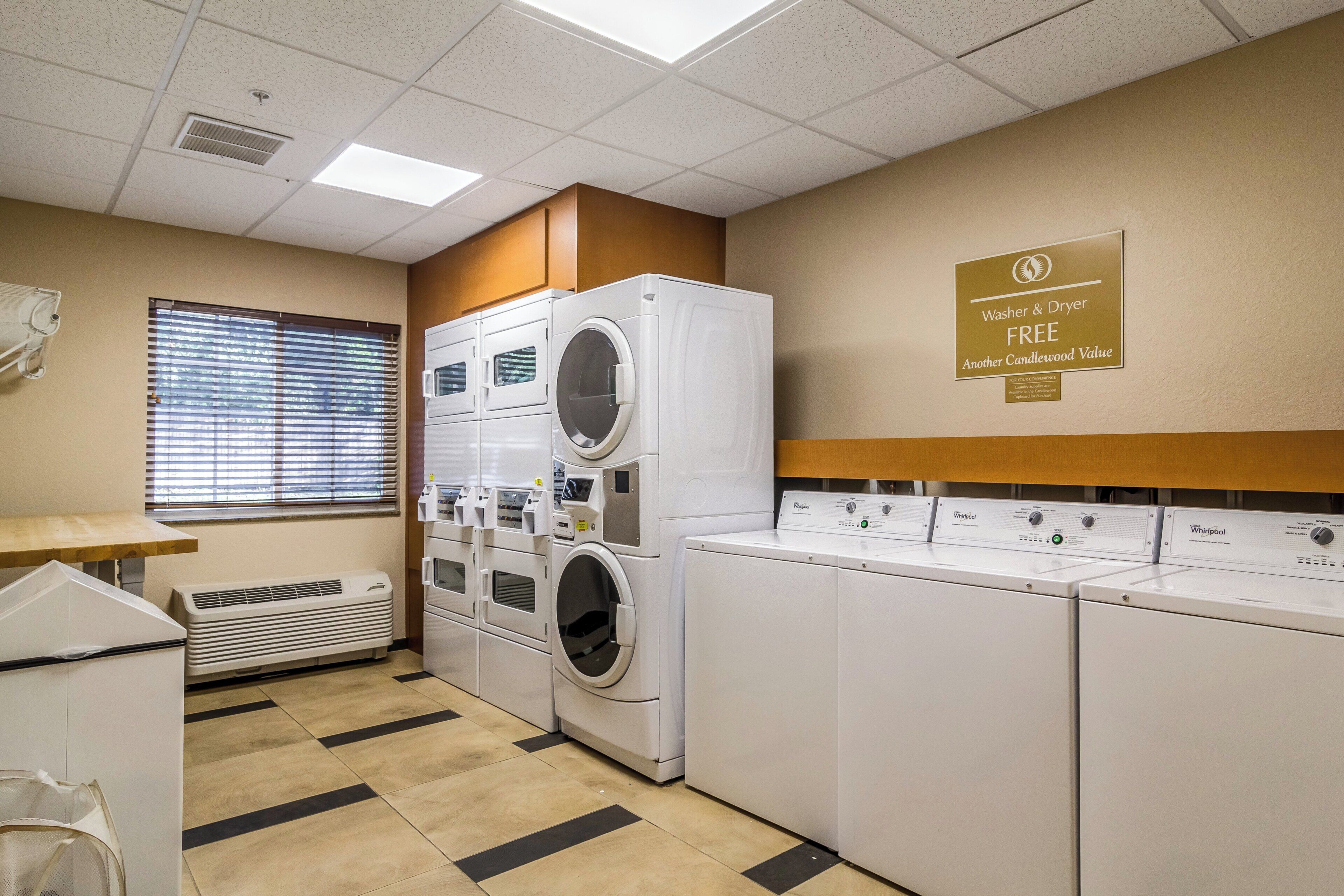 A laundry room with stacked washers and dryers, a vent, and a sign offering free washer and dryer use.