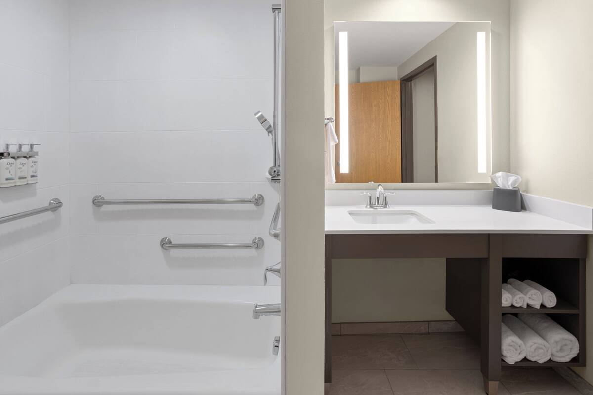 A bathroom with a bathtub, a shower, a sink, and a mirror.