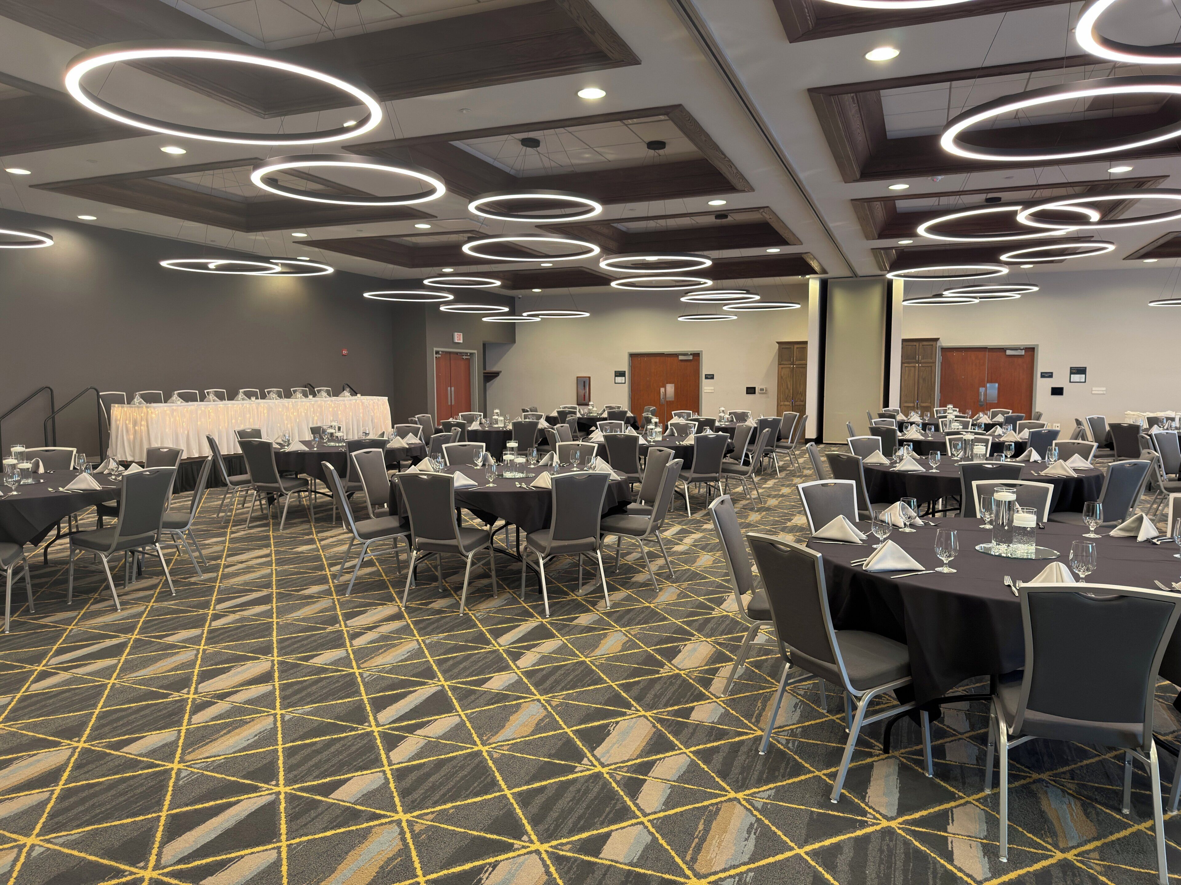 A conference room with tables, chairs, and a patterned carpet.