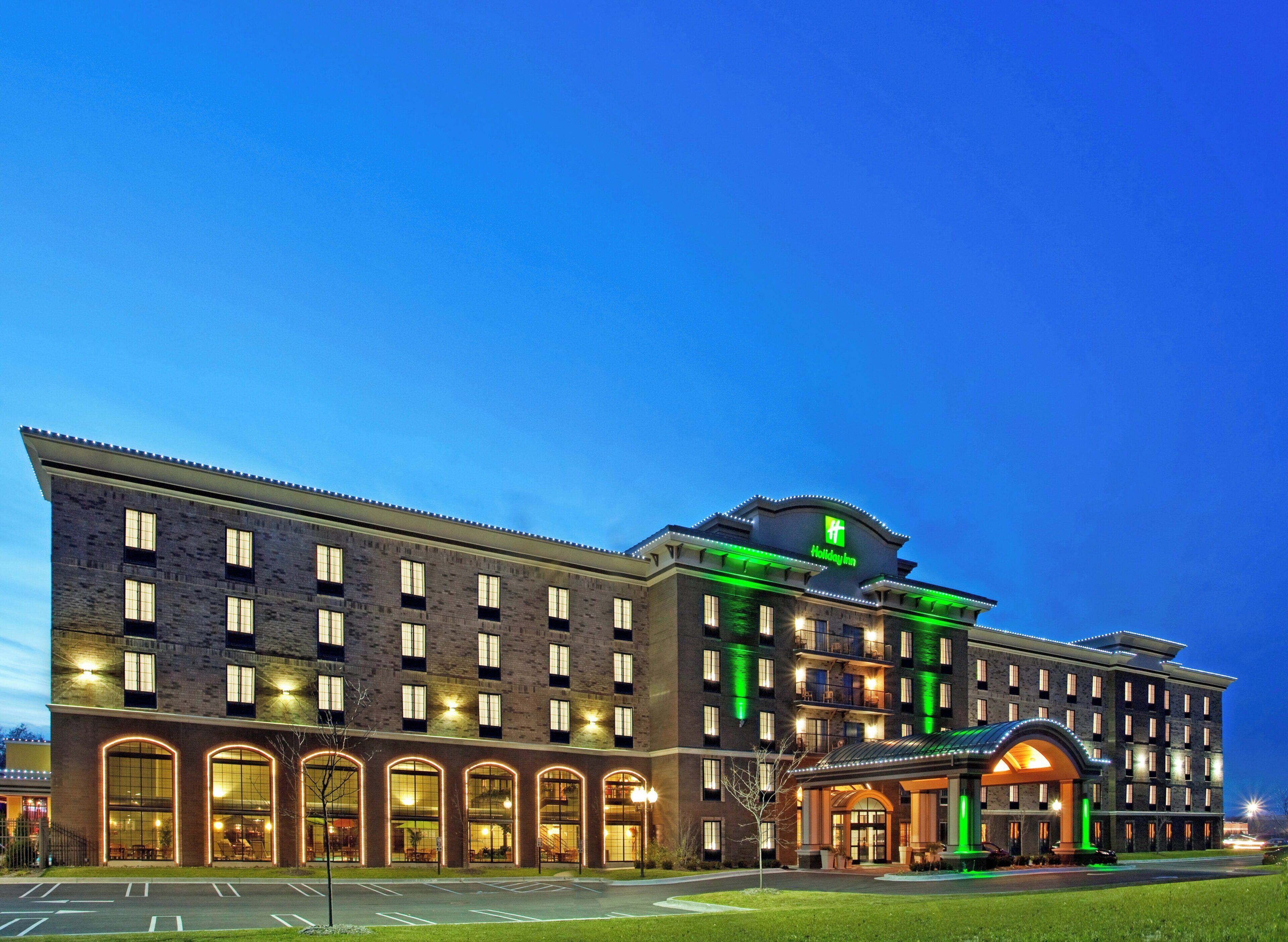 Ein mehrgeschossiges Hotel mit Ziegelverkleidung, großen Fenstern und einem auffälligen, grünen Schild, das es als Holiday Inn kennzeichnet.