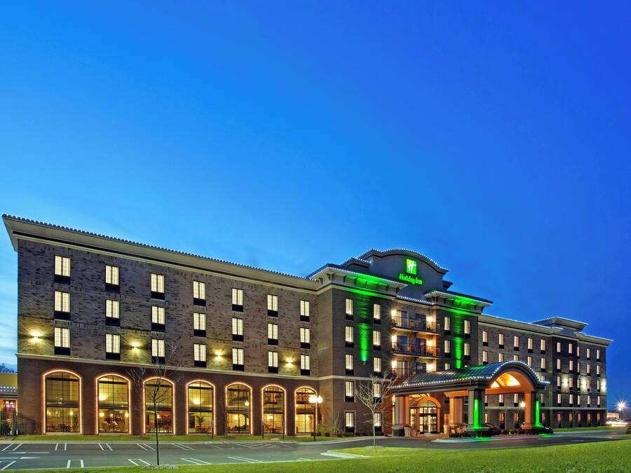 Ein mehrgeschossiges Hotel mit Ziegelverkleidung, großen Fenstern und einem auffälligen, grünen Schild, das es als Holiday Inn kennzeichnet.