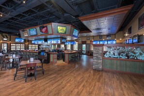 A sports bar with multiple screens, wooden flooring, and a bar area. - Holiday Inn Midland by IHG (Midland)
