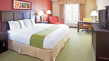 Habitación de hotel con una cama grande, dos mesitas de noche con lámparas, un escritorio con silla, televisión y ventana con cortinas.