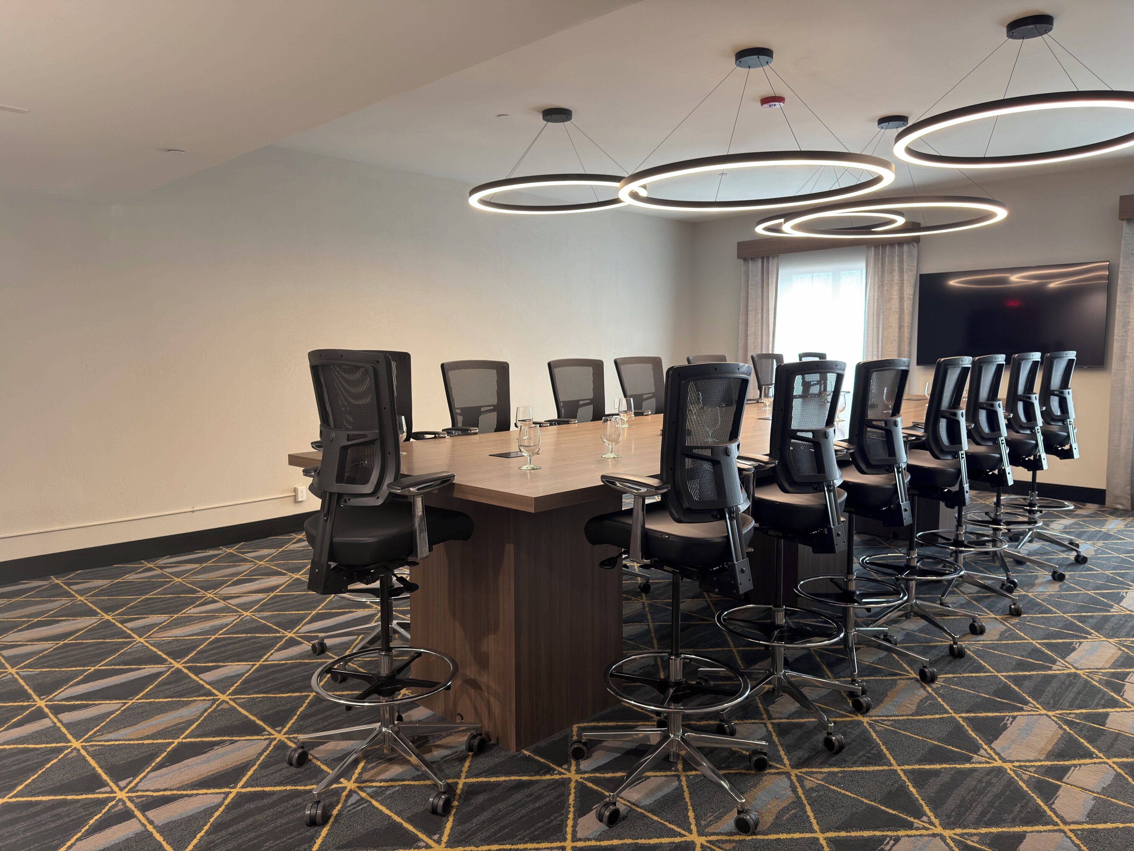 Un salón de conferencias con una larga mesa, varias sillas y un candelabro moderno.