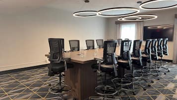 Un salón de conferencias con una larga mesa, varias sillas y un candelabro moderno.