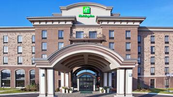 A Holiday Inn hotel with a brick facade, large arched entrance, and a prominent green logo.