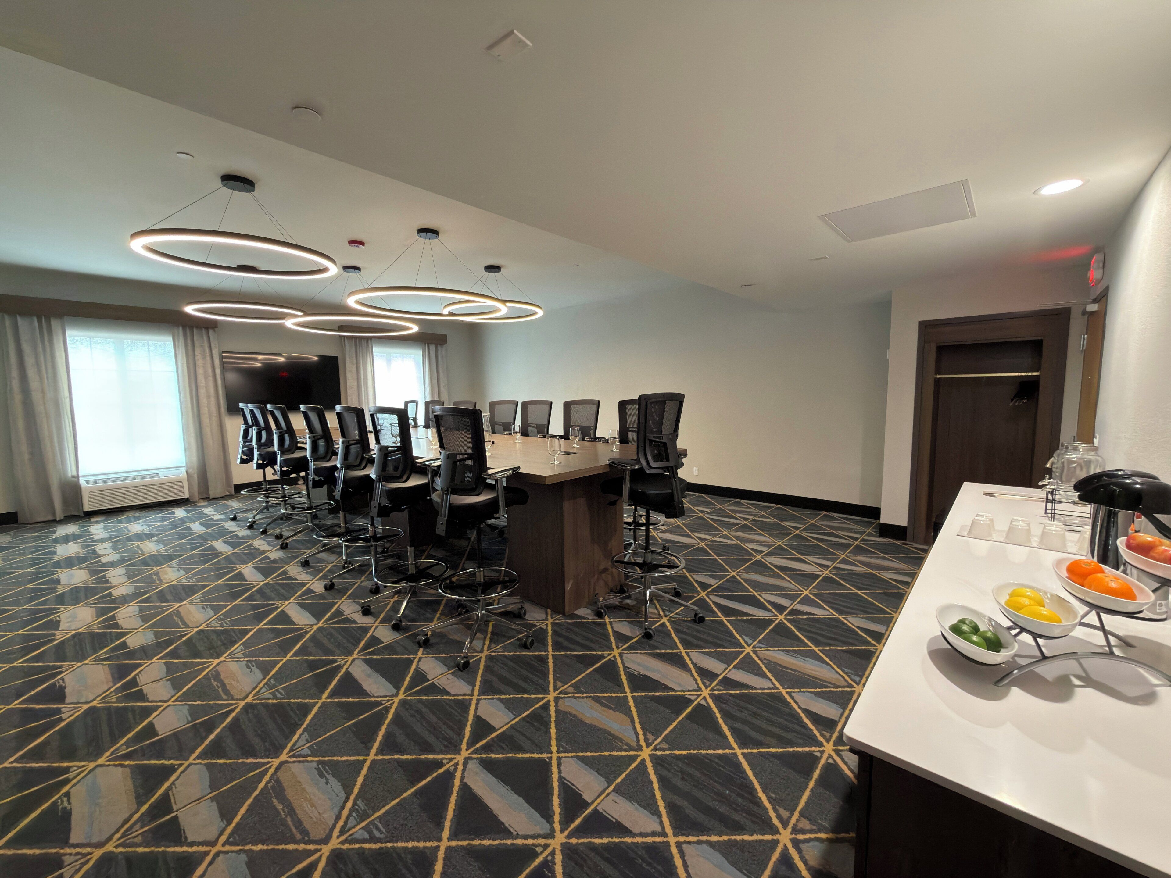 Une salle de conférence équipée d’une grande table, de chaises et d’un buffet garni de fruits.