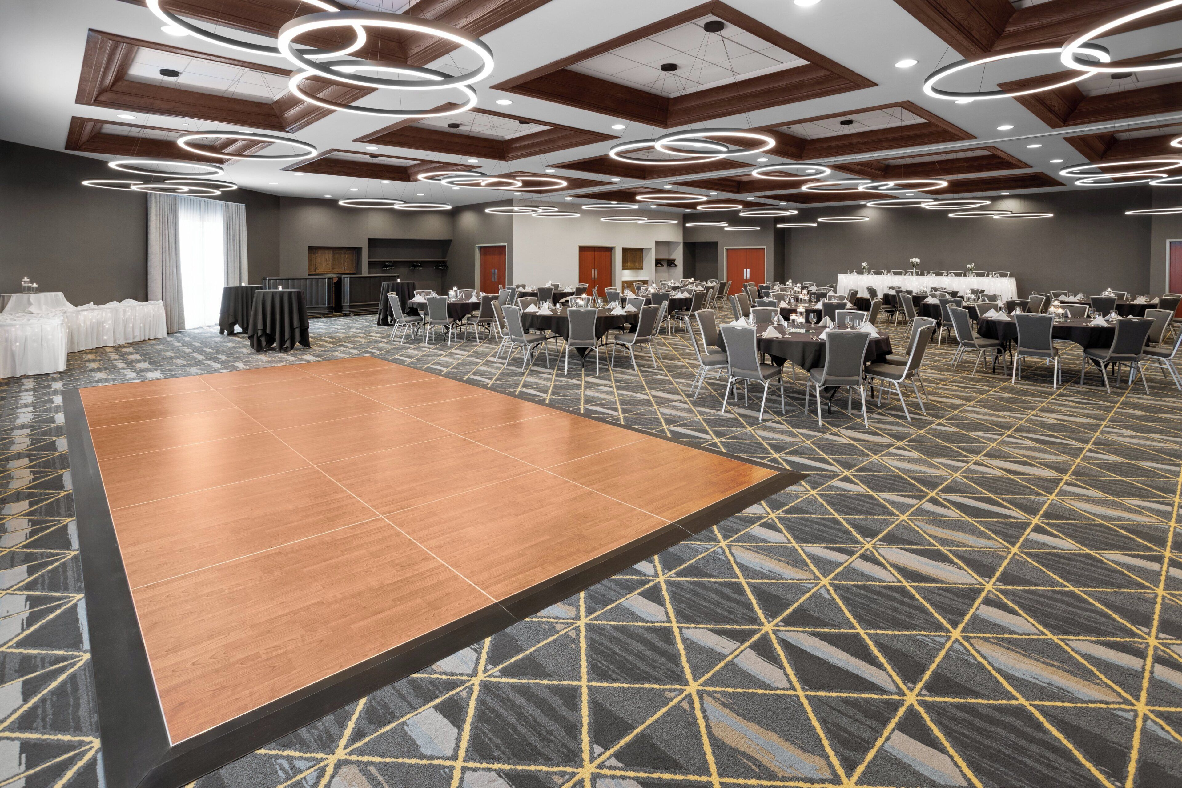 A large conference room with a central table, multiple round tables, and chairs arranged for meetings.