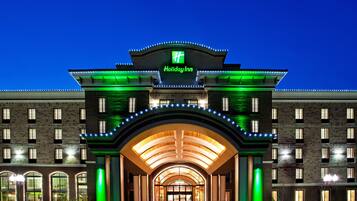 Welcome to the Holiday Inn, featuring a grand arched entrance and a symmetrical facade with evenly spaced windows.